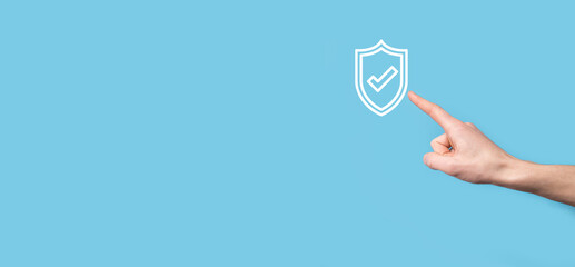 Male hand holding protect shield with a check mark icon on blue background. Protection network security computer and safe your data concept .