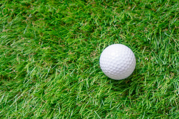 Golf ball on the green artificial grass. Top view background with copy space.