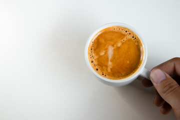A close up of a white coffee cup with coffee on a white background.