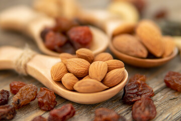 Almonds, apricot seed on a wooden spoons. Raisins, cashews, figs, nuts on top of a wooden board.