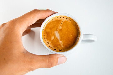 A close up of a white coffee cup with coffee on a white background.