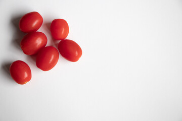 A close up of red cherry tomatoes on a white background.