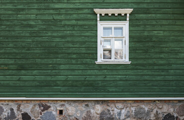 Window with white frame in an old green wall