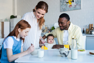 happy multiethnic family smiling during breakfast in kitchen