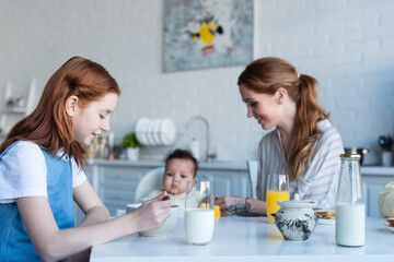 Obraz na płótnie Canvas preteen girl having breakfast near mother and infant african american sister