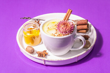 Golden turmeric milk with ice on bright yellow background