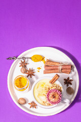 Golden turmeric milk with ice on bright yellow background