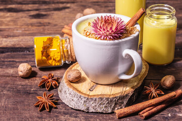 Golden turmeric milk with ice on bright yellow background