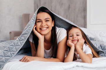 Delighted mother lying in bed with a child