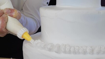 Pastry chef squeezes buttercream onto the cake. Chef decorate a cake with a pastry bag or bag sleeve at the bakery