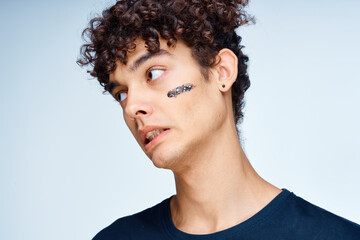 Obraz premium curly-haired guy in a black t-shirt cosmetics on the face clean skin