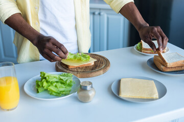 cropped view of african american man preparing sandwiches in kitchen
