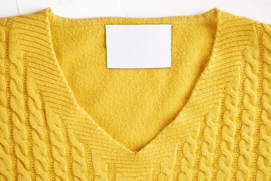 Closeup of an inner label on the neck of a pretty yellow wool sweater. Blank space to place a logo, text or image