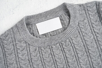 Mockup of an inner label on the neck of a pretty gray wool sweater. Blank space to place a logo,...