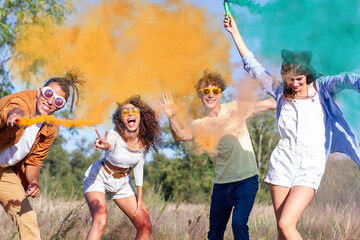 Beautiful young man and woman hold light up colored smoke bombs - Happy friends having fun in the...