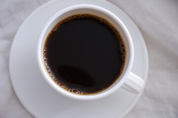 Obraz na płótnie Canvas White cup of black coffee in a white bed.