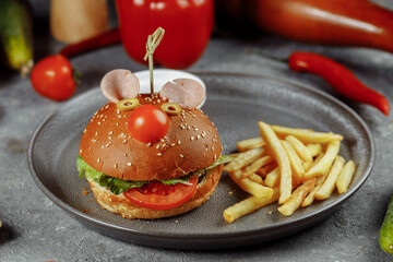 Children's burger in the form of a mouse. Burger from the children's menu with fries and sauce