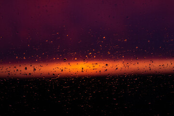 Rain drops on the window on the sunsret (dark-blue pink background)