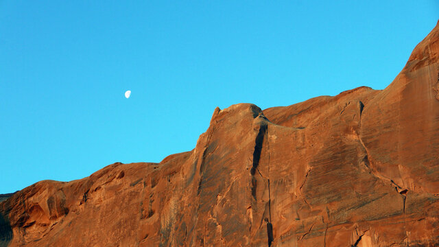 Half moon over red rocks in Monument Valley