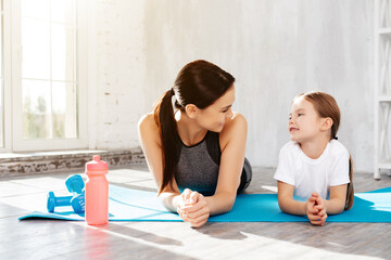 Charming girl and her mother having break after exercising