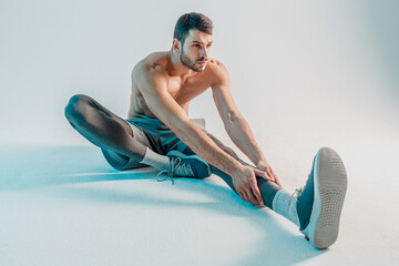 Sportsman stretching leg before training in studio