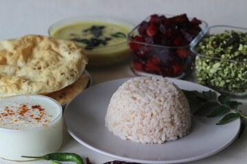 Vegetarian meals prepared in Kerala style. The serving includes boiled red rice, lentil curry, stir fried beetroot and potato, Stir fried French beans, curd and pappad.