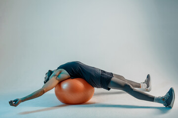 Sportsman lying on fitness ball after training