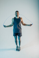 Serious young sportsman jumping with skipping rope - obrazy, fototapety, plakaty
