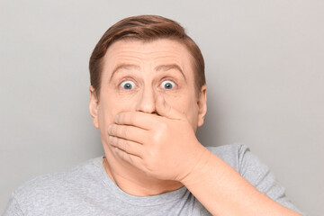 Portrait of shocked frightened man covering mouth with hand