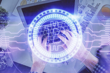 Double exposure of man's hands typing over computer keyboard and crypto currency theme hologram...