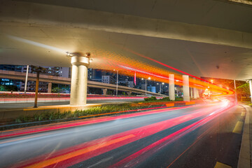 Overpass and red light trails at night on the illuminated highway