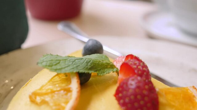 closeup of a slice of raw mango passionfruit cake garnished with strawberries and blueberries.