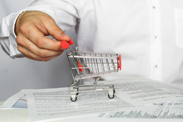 A mini shopping cart held by a man in a white shirt. business