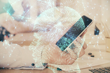 Double exposure of man's hand holding and using a digital device and brain hologram drawing. Data concept.