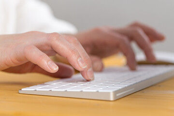 Fototapeta na wymiar Woman office worker typing on white keyboard
