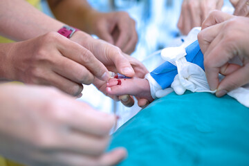 Doctor holding baby’s foot and injecting with needle to baby’s foot for drawing blood sample in...