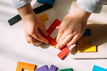 The child creates a figure from a colored puzzle on the table
