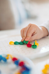 The child sticks the mosaic into the shape with his fingers