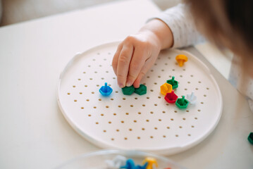 A toddler assembles a mosaic from small parts