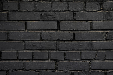 A black brick wall. Background with a brickwork texture. The walls of street houses. Loft style.