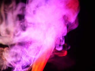 Abstract colour series. Composition of colourful smoke in motion. Fusion of red and pink mist isolated on a dark background to inspire creativity.