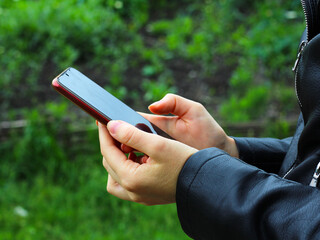the girls are holding the phone in their hands. Side view shot of woman's hands using smart phone in nature, online shopping concept.