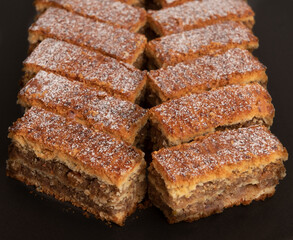 brown cake pieces aligned on black plate. White sugar ornament