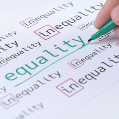 Obraz premium A hand with a green marker underlines the word EQUALITY surrounded by the words INEQUALITY.. Selective focus