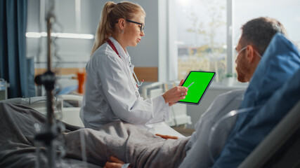 Fototapeta premium Hospital Ward: Friendly Female Doctor Talks to Sick Male Patient Resting in Bed, Shows Green Chroma Key Screen Tablet Computer, Explains Results. Physician Talks to Man Recovering after Surgery