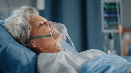 Hospital Ward: Portrait of Beautiful Elderly Woman Wearing Oxygen Mask Sleeping in Bed, Fully...