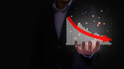 Business downturn, decline, loss, failure concept. Businessman is showing hologram financial stok investment report graph in bar chart on his hand with red arrow point down in dark background.