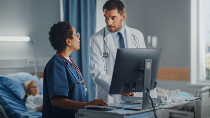 Hospital Ward: Caucasian Doctor Talks With Professional Black Head Nurse, They Use High-Tech Computer. In Background Patient in Bed Recovering after Successful Surgery. Health Care Specialists