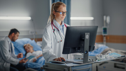 Hospital Ward: Professional Female Doctor or Surgeon Uses Medical Computer. In the Background ModernEquipment Clinic Doctor Sitting and Caring for Patient Recovering After Successful Surgery in Bed - obrazy, fototapety, plakaty
