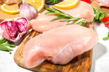 Various raw chicken meat portions. Set of uncooked chicken fillet, thigh, wings, strips and legs on white cooking table background with spices